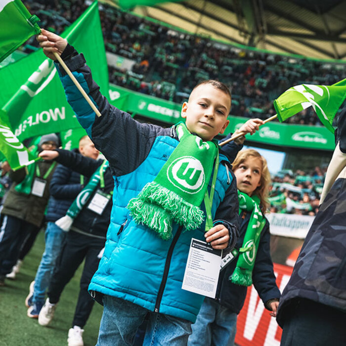 Ein junger VfL-Fahne schwenkt eine Fahne während der Wölfi-Runde im Innenraum der Volkswagen Arena während eines Heimspiels des VfL Wolfsburg.