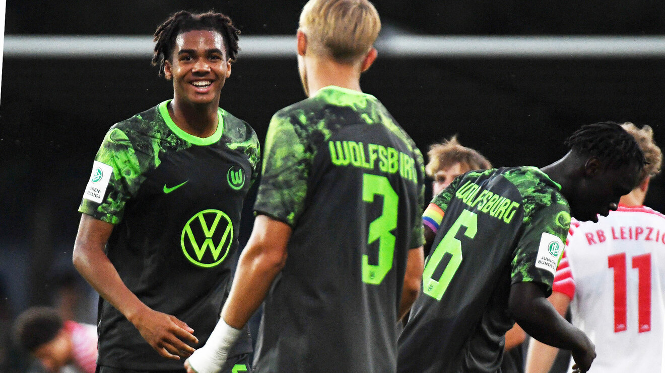 VfL-Wolfsburg-Spieler David Odogu lacht auf dem Feld in die Kamera.