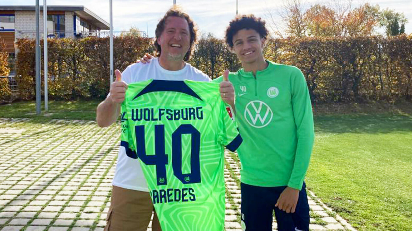 VfL Wolfsburg Spieler Paredes posiert mir einem Fan, der ein Trikot mit Paredes' Rückennummer in die Kamera hält.