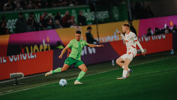 Kilian Fischer spielt den Ball auf dem Spielfeld der Volkswagen Area, während ein Gegenspieler auf ihn zukommt.