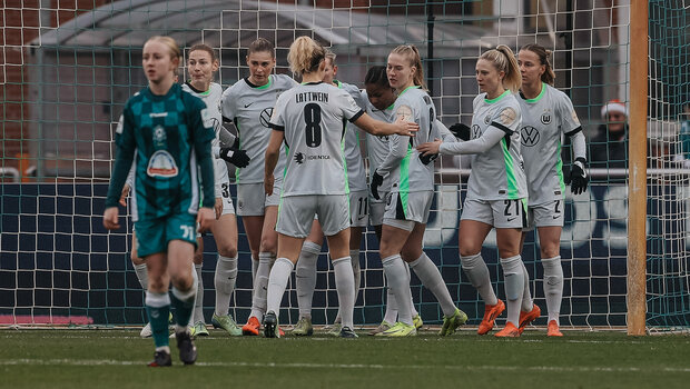 Die Mannschaft der VfL-Wolfsburg-Frauen juben miteinander vor einem Tor.