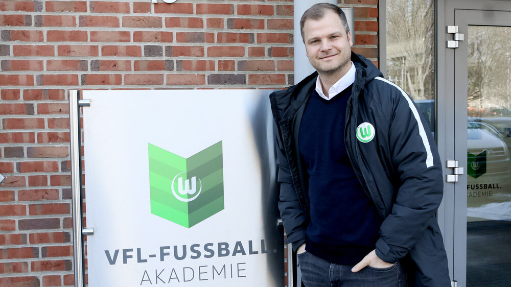 Fabian Wohlgemuth vor dem Schild der VfL Fußball Akademie.