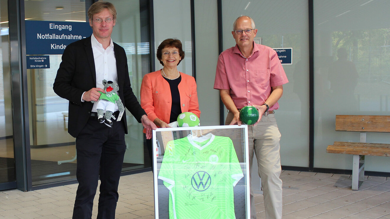 VfL Wolfsburg Geschäftsführer Tim Schumacher überreicht ein signiertes Trikot des VfL Wolfsburg.