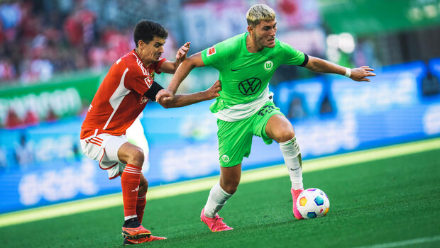 Der VfL Wolfsburg-Spieler Jonas Wind wird von seinem Gegenspieler am Trikot festgehalten.