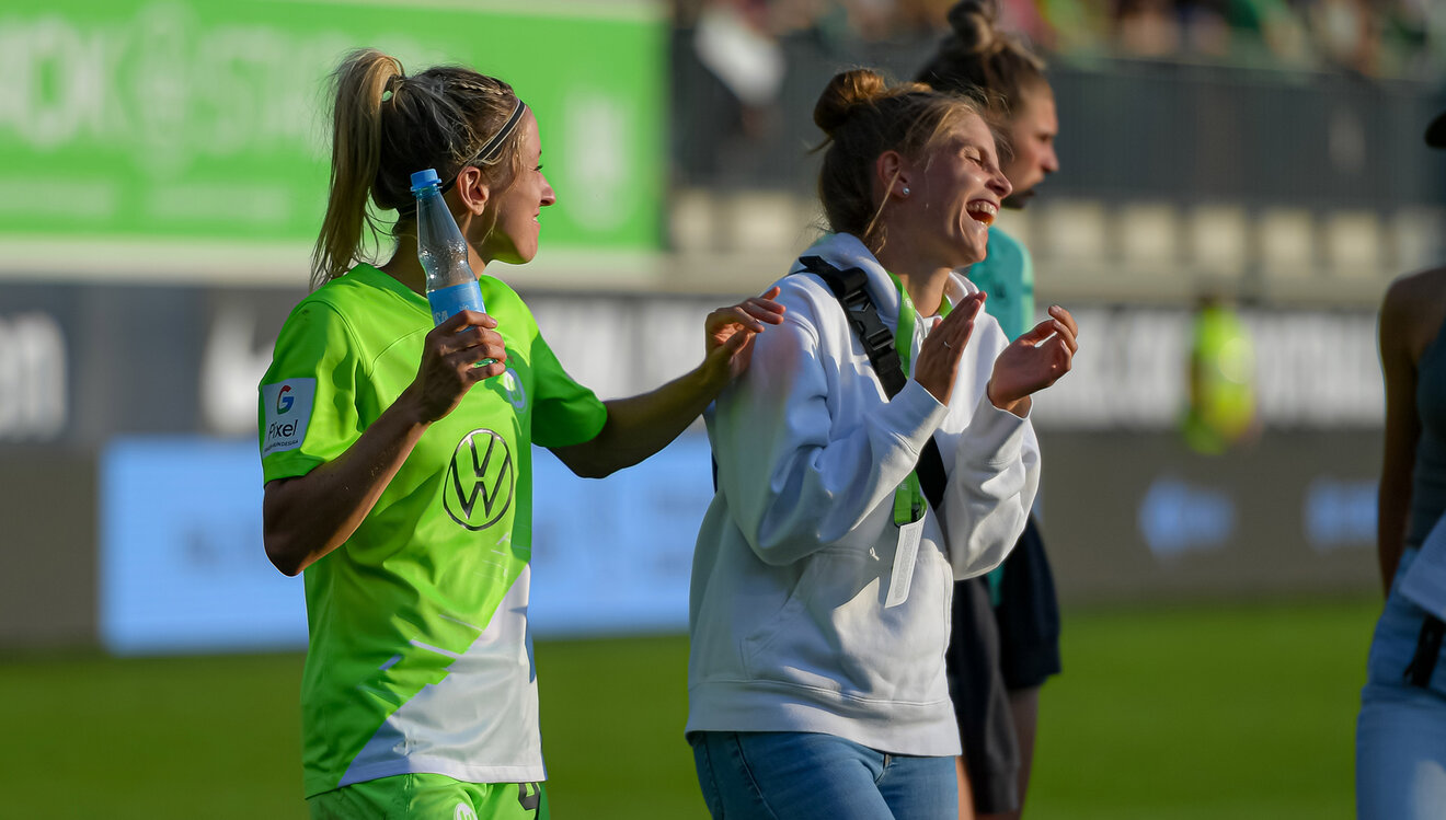 Die VfL-Wolfsburg-Spielerinnen Kathrin Hendrich und Tabea Sellner lachen gemeinsam nach dem Sieg.