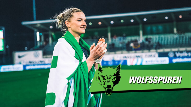 VfL Wolfsburg Spielerin Alexandra Popp läuft mit einer VfL Wolldecke um den Schultern über den Rasen des AOK-Stadions und klatscht lächelnd in die Hände.