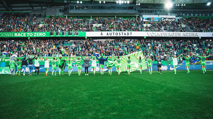 Die Spielerinnen vom VfL Wolfsburg jubeln mit den Fans.