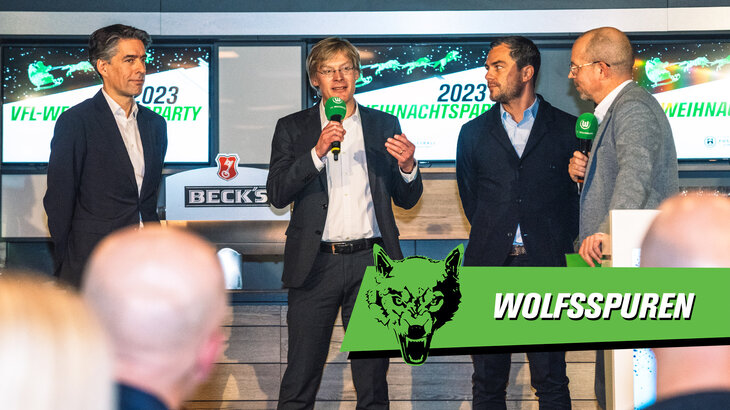 Die Geschäftsführer des VfL Wolfsburg sprechen bei der Weihnachtsfeier auf dem Podium zu den Angestellten.