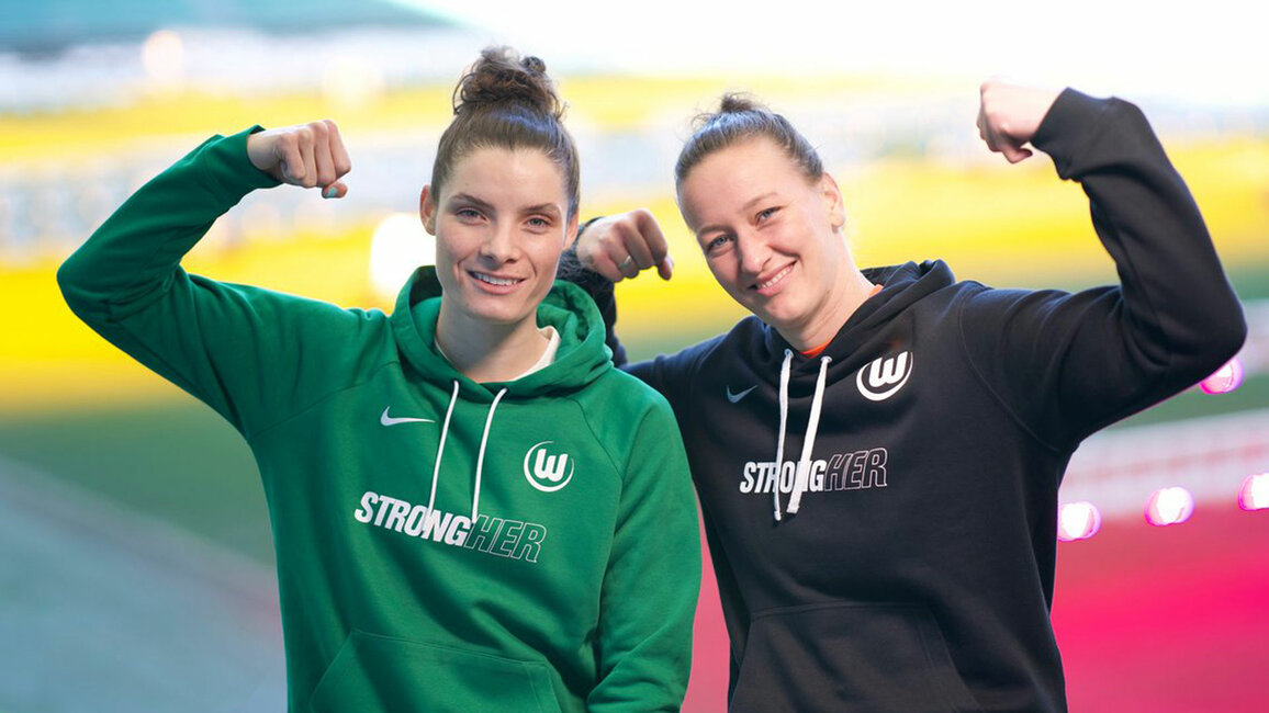 Zwei Spielerinnen des VfL Wolfsburg posieren mit dem neuen StrongHER Hoodie.
