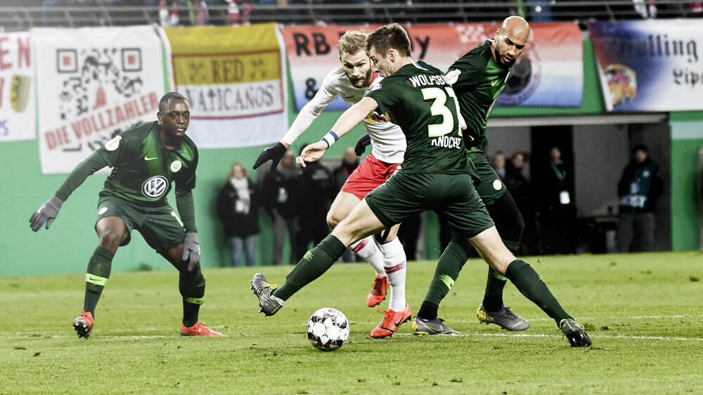 VfL Wolfsburg Spieler Knoche im Zweikampf mit einem Gegenspieler aus Leipzig um den Ball.
