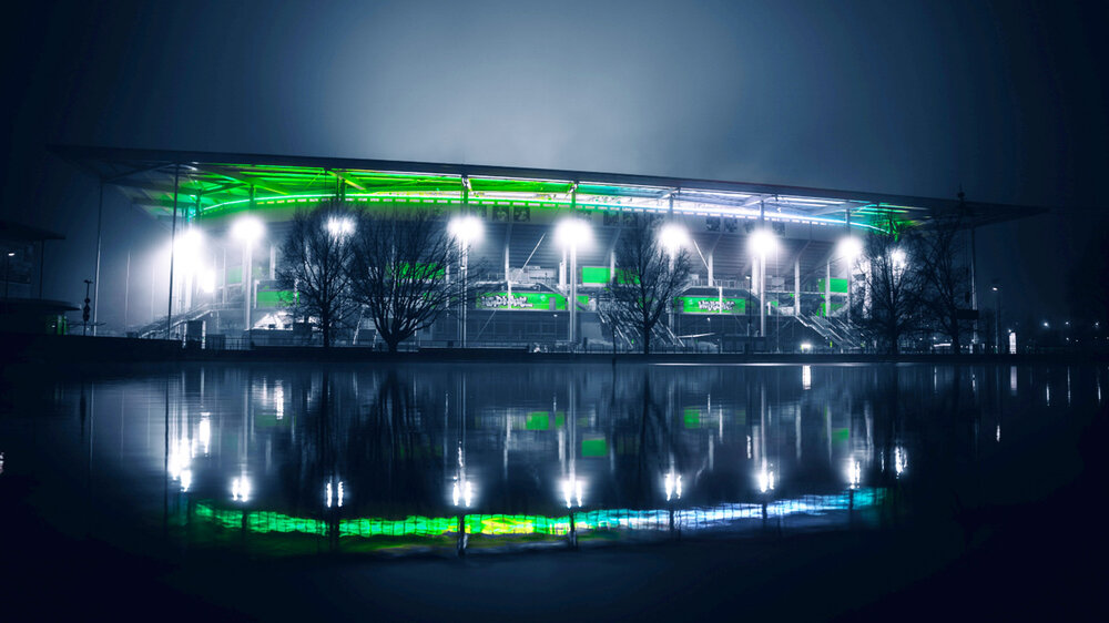 Die Volkswagen Arena vom VfL Wolfsburg bei Nacht grün-weiß beleuchtet.