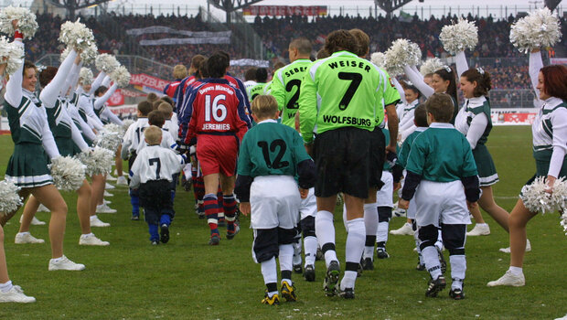 Die Mannschaften vom VfL Wolfsburg und Bayern München laufen mit Kindern an den Händen auf das Spielfeld.