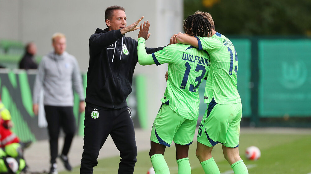 Daniel Bauer bejubelt mit zwei Spielern der U19-Mannschaft des VfL Wolfsburg ihren Sieg.