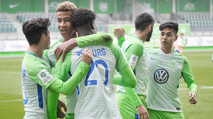 Die Spieler der U19-Mannschaft des VfL Wolfsburg liegen sich in den Armen und jubeln.