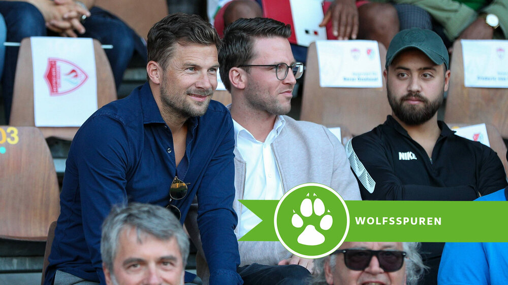 Der ehemalige VfL Wolfsburg-Spieler Daniel Baier sitzt lächelnd auf der Tribüne.