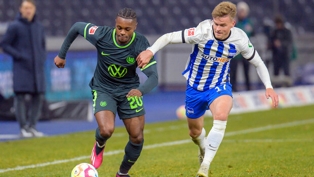 Der VfL-Wolfsburg-Spieler Ridle Baku setzt sich erfolgreich gegen einen Spieler durch.