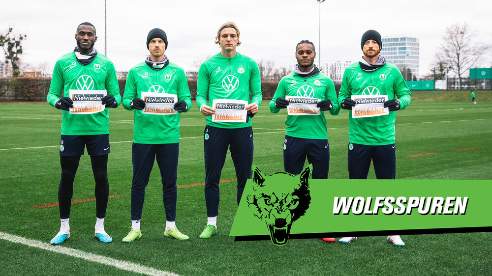 Fünf Spieler des VfL Wolfsburg halten Schilder mit der Aufschrift Nie Wieder. 