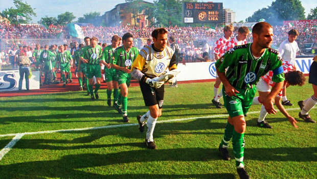 Spieler des VfL Wolfsburg laufen auf das Spielfeld ein.