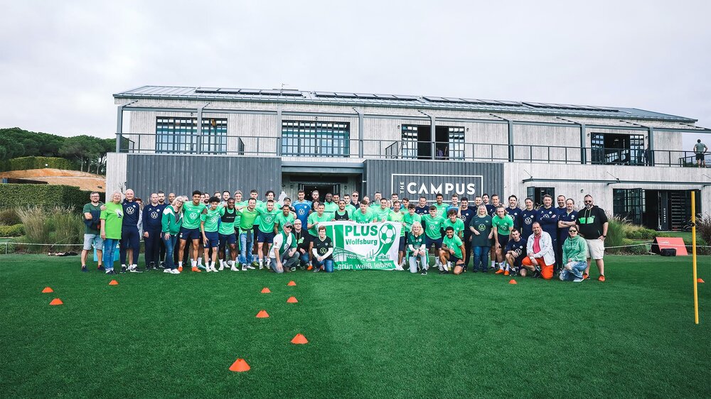 Die Mannschaft des VfL-Wolfsburg posiert mit den mitgereisten Fans auf einem Gruppenfoto auf dem Trainingsgelände in Portugal.