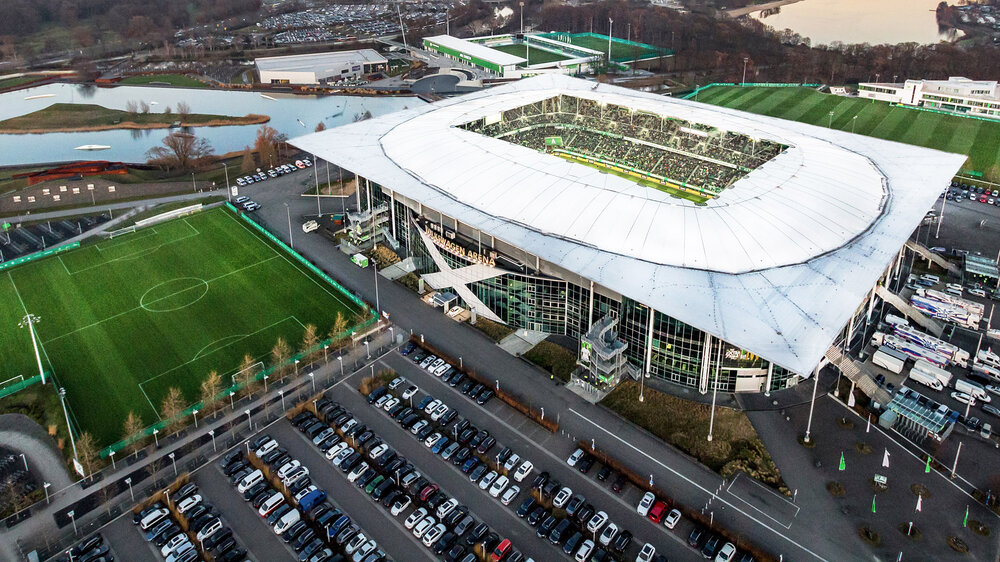 Die Volkswagen Arena sowie die angrenzenden Parkplätze, Trainingsplätze und der Allersee von oben.