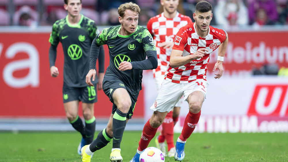 VfL Wolfsburg Spieler Cozza läuft auf dem Spielfeld hinter einem Gegner her.