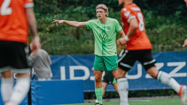 VfL-Wolfsburg-Spieler Sebastiaan Bornauw gibt auf dem Rasen Anweisungen an seine Mitspieler.