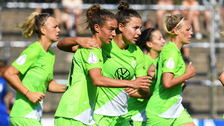 Die VfL Wolfsburg Frauen umarmen sich und laufen über das Spielfeld.