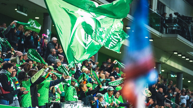 Fans der Frauen vom VfL Wolfsburg sitzen im Stadion.