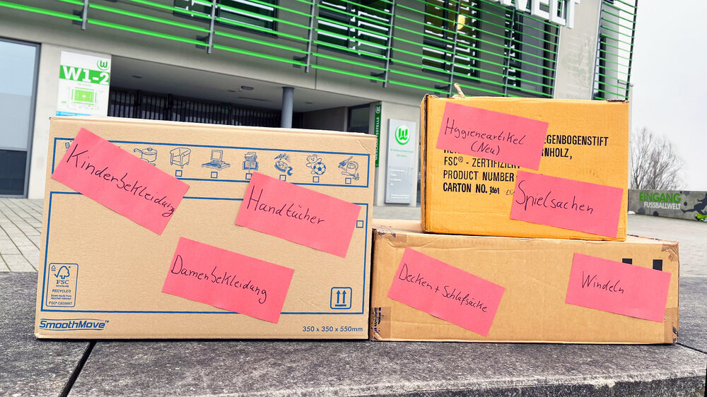 Kisten mit Spenden stehen vor dem AOK Stadion des VfL Wolfsburg.
