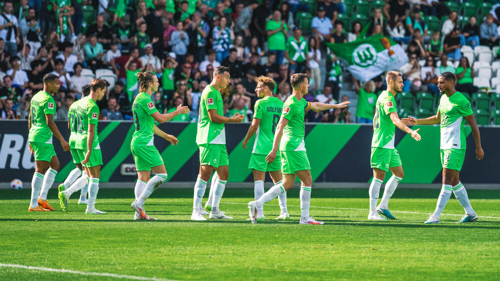 Das Männerteam des VfL Wolfsburg jubelt auf dem Platz.