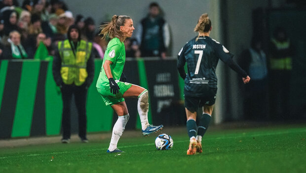 Eine Spielein des VfL Wolfsburg nimmt auf dem Spielfeld den Ball an, eine Gegnerin kommt auf sie zu gelaufen.