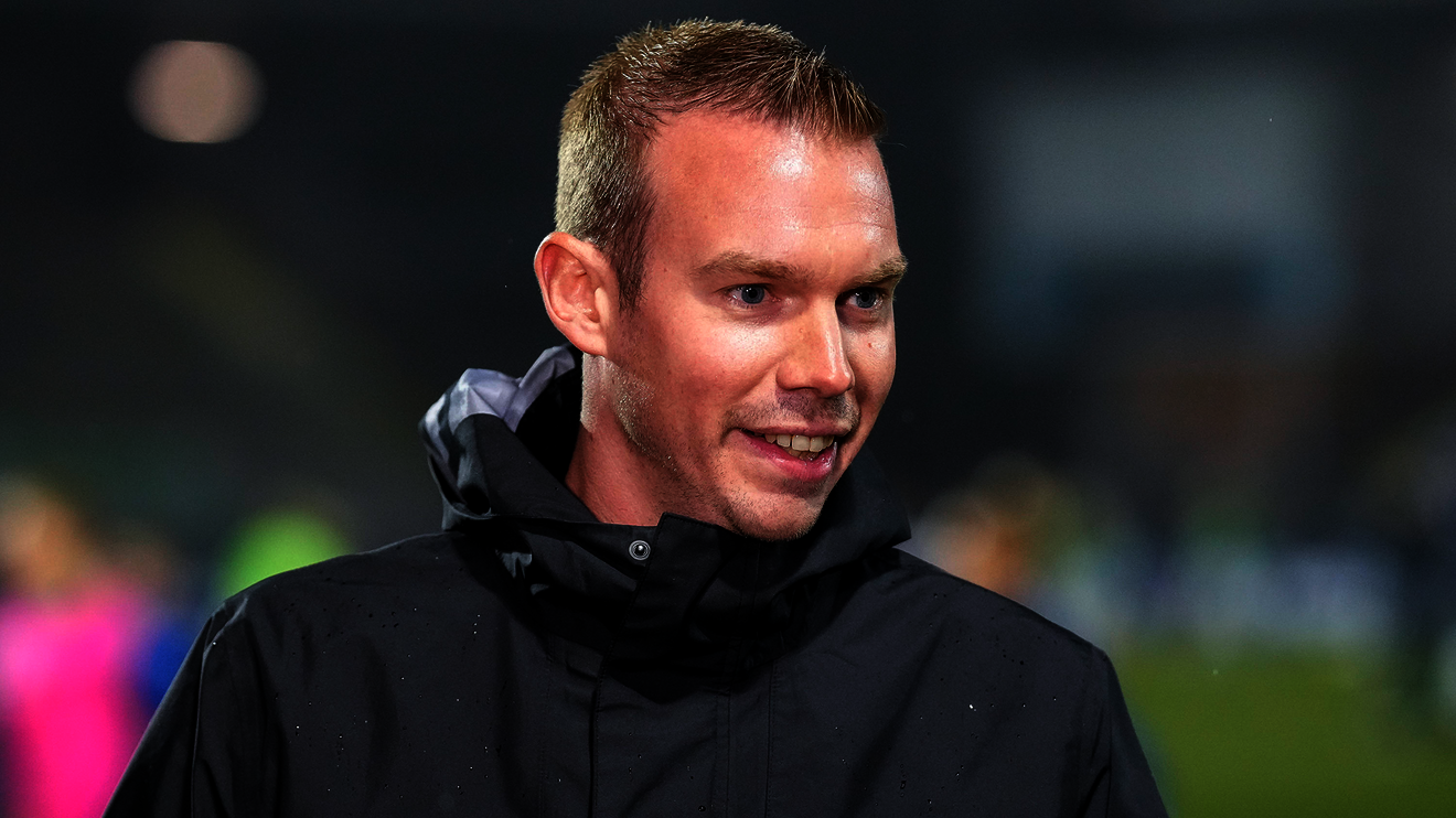 VfL-Wolfsburg Trainer Tommy Stroot lächelt in die Kamera.