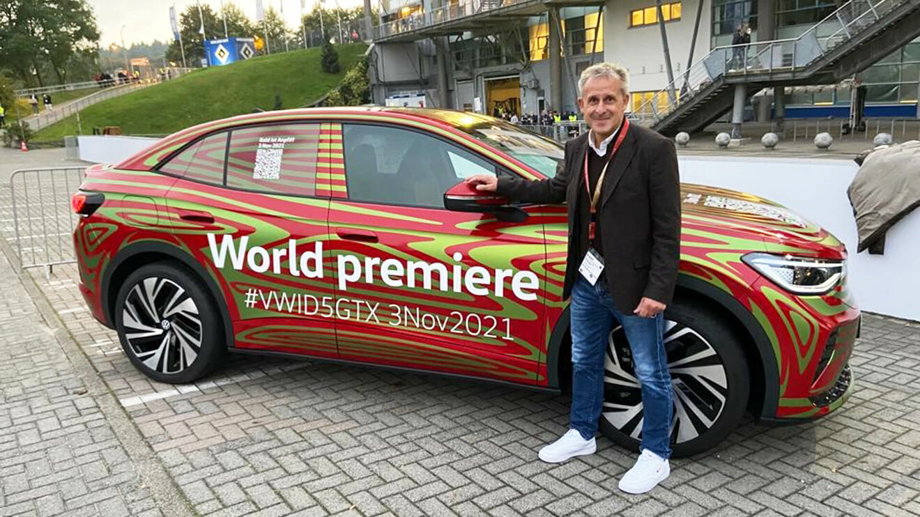 VfL Wolfsburg-Funktionär Littbarski posiert mit dem neuen VW ID5 GTX.