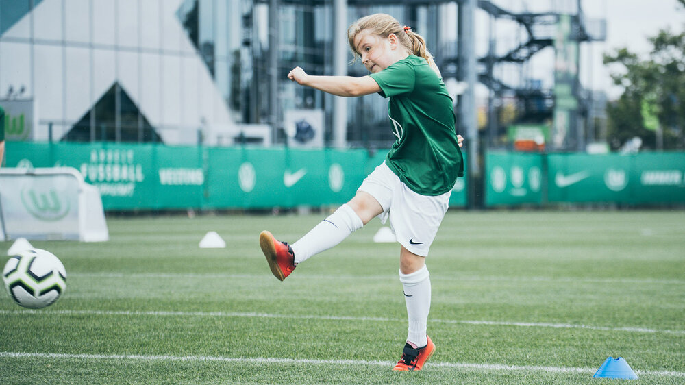 Ein Mädchen schießt einen Ball beim Kindertraining des VfL Wolfsburg.