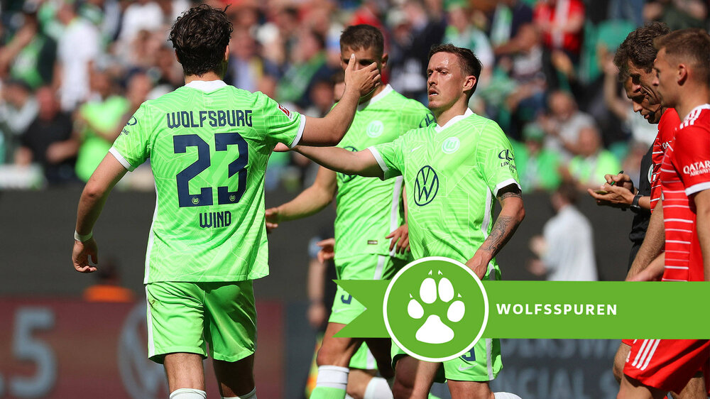 Die VfL-Wolfsburg-Spieler Jonas Wind und Max Kruse klatschen sich ab. Darunter ist der Schriftzug "Wolfsspuren".
