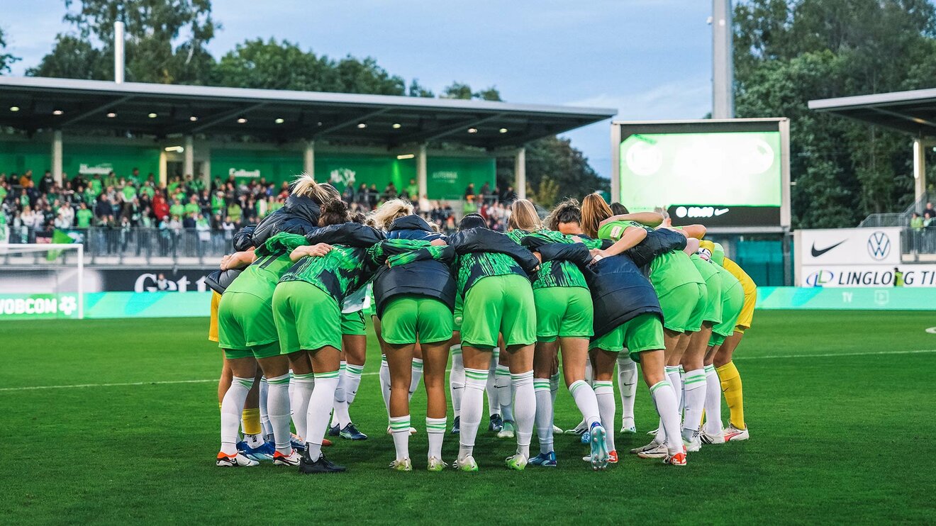 Die Spielerinnen des VfL Wolfsburg legen ihre Arme umeinander, beugen sich nach vorne und bilden einen Kreis.