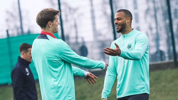 VfL-Wolfsburg-Spieler Kevin Behrens und Lukas Nmecha lachen zusammen.