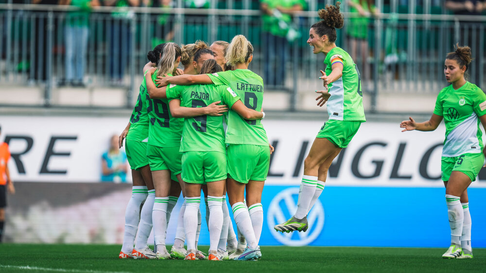 Das Team der VfL Wolfsburg Frauen jubelt nach dem Tor und Dominique Janssen springt zu dem Team. 