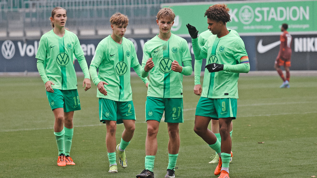 Vier U17-Spieler des VfL Wolfsburg laufen nebeneinander über das Spielfeld.