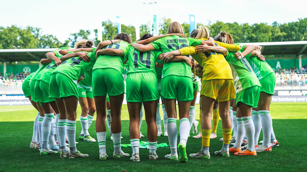 Die Spielerinnen des VfL Wolfsburg stehen in einem Mannschaftskreis zusammen.