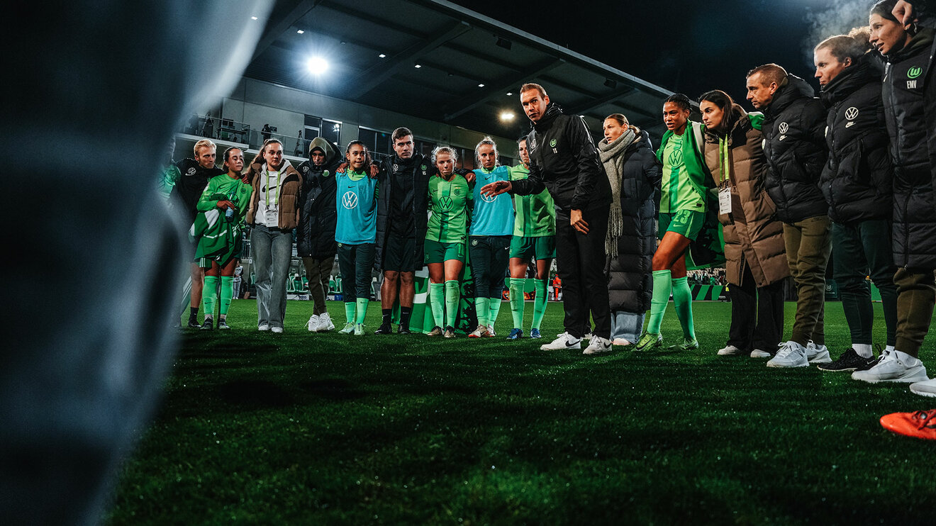Der VfL-Wolfsburg-Trainer Tommy Stroot steht im Mannschaftskreis redet mit dem Team.