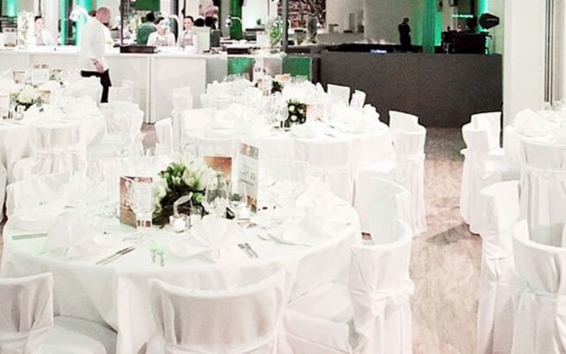 Eine Galaveranstaltung mit weiß gedeckten Tischen und Stühlen in der Event-Halle des VfL Wolfsburg.