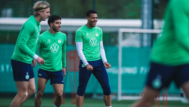 Der VfL-Wolfsburg-Spieler Felix Nmecha lacht mit Teamkollege Paulo Otavio während der Trainingseinheit.
