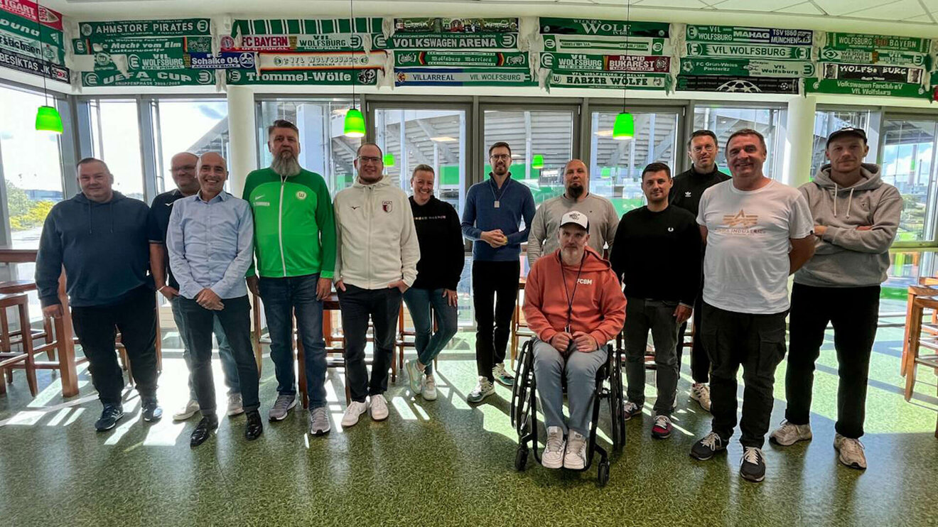 Die Fanbeauftragten stehen nebeneinander im Fanhaus des VfL Wolfsburg.