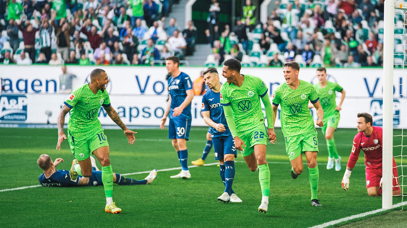 VfL-Wolfsburg-Spieler Lukas Nmecha, mit seinem Bruder Felix Nmecha, die zusammen auf dem Fußballplatz sind und aufeinander zulaufen.