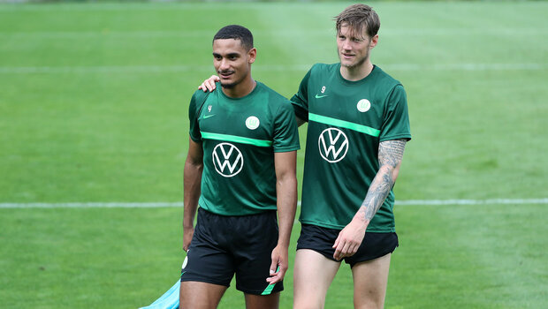 Wout Weghorst legt im Training der VfL Wolfsburg Lizenzmannschaft seinen Arm um Maxence Lacroix.