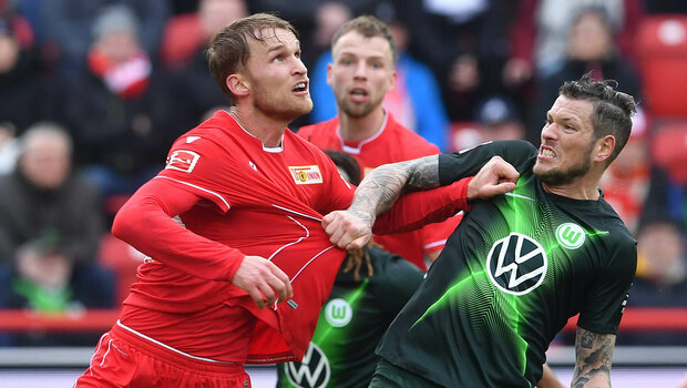 Ein Spieler des VfL Wolfsburg zieht seinem Gegenspieler am Trikot.