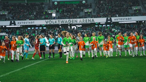 Die Einlaufkinder laufen von den Spielerinnen des VfL Wolfsburg und von Eintracht Frankfurt weg vom Platz.