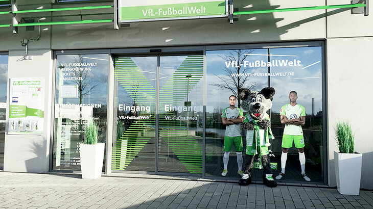 VfL Wolfsburg-Maskottchen Wölfi steht vor dem Eingang der VfL-FußballWelt.