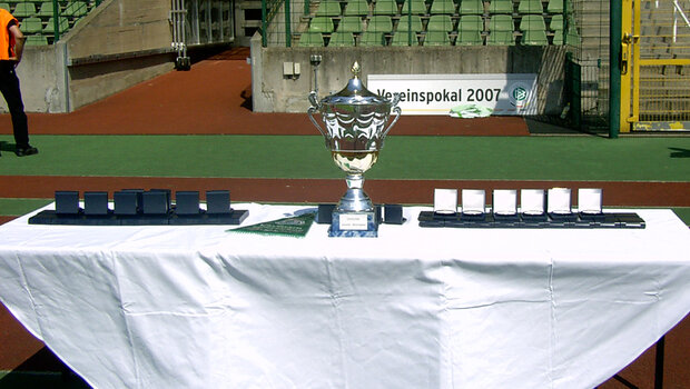 Der Pokal der U19 2007 steht auf einem Tisch. Daneben stehen die Medaillien.